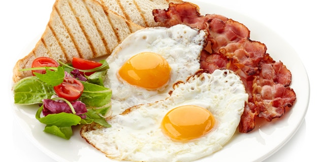 Plate of breakfast with fried eggs, bacon and toasts