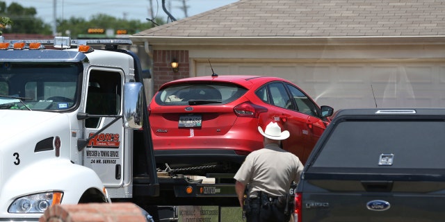 A vehicle is towed as Denton County Sheriff's officers investigate the crime scene.
