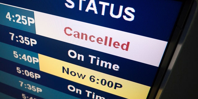 Flight cancelled notice on an airport arrival departure board sign.