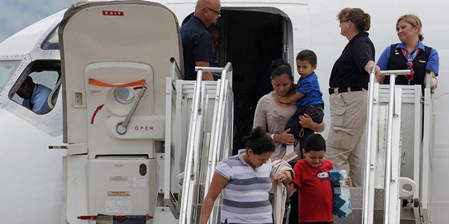Women hold their children while disembarking from a plane at the Soto Cano military base in Comayagua August 11, 2014. The plane carrying 11 women and 14 children landed at the base after they had been deported from the U.S. While the White House says the number of Central American child migrants crossing the U.S. border has fallen sharply, the big unanswered question remains why. The U.S. government has pointed to the seasonal weather. However, Reuters reporting in southern Mexico and Central America shows it is due to a combination of factors, including tighter border policing, horror tales told by deportees who grappled with drug gangs, an advertising blitz touting the dangers of making the journey and the high-profile arrests of several human smugglers, or coyotes. Picture taken August 11. To match Insight USA-IMMIGRATION/DECLINE REUTERS/Jorge Cabrera (HONDURAS - Tags: SOCIETY IMMIGRATION POLITICS MILITARY TRANSPORT) - RTR422BX