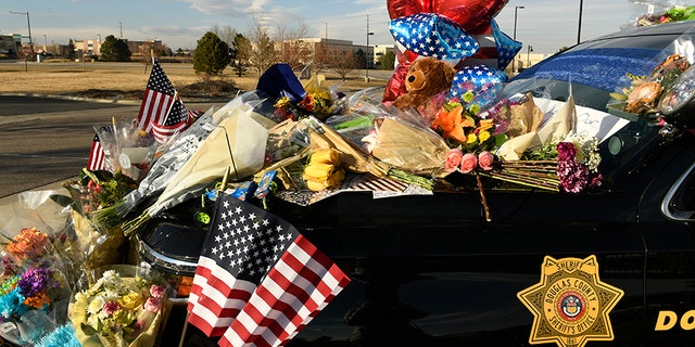 A memorial is seen on a police cruiser for the victims of what authorities describe as an ambush Monday, Jan. 1, 2018, at the Douglas Country Sheriff Substation in Highlands Ranch, Colo.