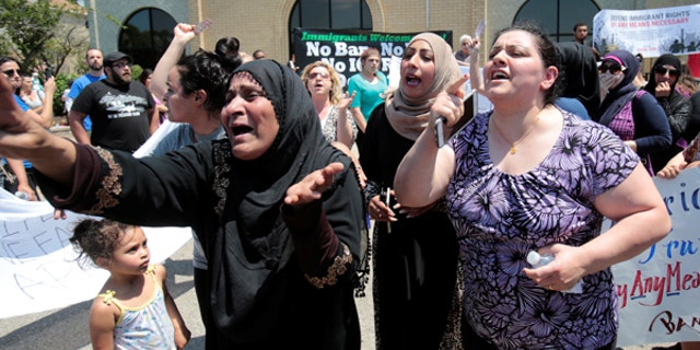 A group of women react as they talk about family members seized on Sunday by Immigration and Customs Enforcement agents during a recent rally in Southfield, Michigan.