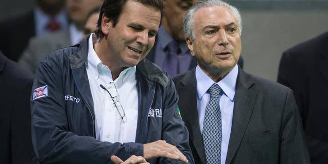 Brazil's interim President Michel Temer, right, talks to Rio de Janeiro Mayor Eduardo Paes as they visit Olympic Park in Rio de Janeiro, Brazil, Tuesday, June 14, 2016. In recent weeks Temer has stepped up his pledges of support for Rio games, which have been beset by a series of problems including the ongoing political crisis, Brazil's worst recession in decades and an outbreak of the Zika virus, which has been linked to birth defects in infants. (AP Photo/Felipe Dana)