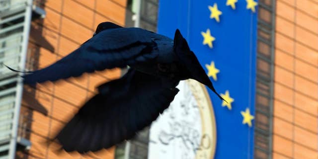 WITH STORY BRITAIN EU FUTURE - In this Nov. 20, 2012 file photo, a bird flies in front of a giant banner for the euro currency in front of EU headquarters in Brussels. Issues such as migration, economic stagnation and terror attacks could weigh heavily on voters minds when they go to the polls to cast their ballot during the In-Out EU referendum which takes place on June 23, 2016. (AP Photo/Virginia Mayo, File)