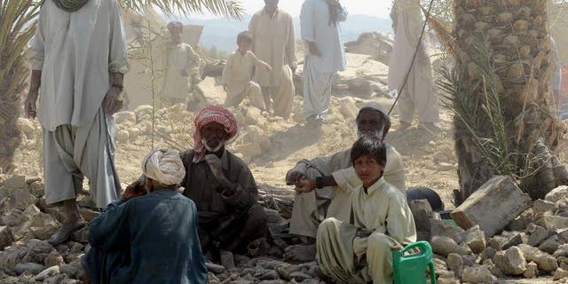 Pakistani earthquake survivors rest near their collapsed mud houses in the earthquake-devastated district of Awaran on September 25, 2013