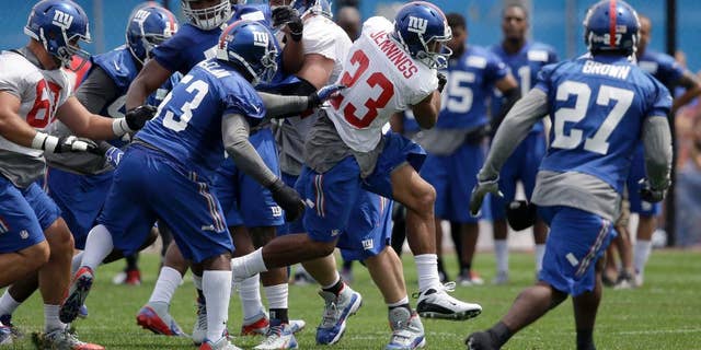 New York Giants' Rashad Jennings (23), center, runs through traffic during NFL football camp in East Rutherford, N.J., Thursday, July 24, 2014. (AP Photo/Seth Wenig)