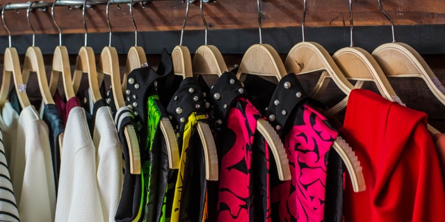 Many blouses on hangers in the dressing room.