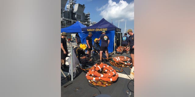 Divers search for missing sailors trapped in a warship off the coast of Singapore.