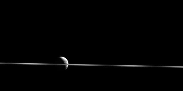 Dione appears cut in two by Saturn's razor-thin rings, seen nearly edge-on in a view from NASA's Cassini spacecraft. This scene was captured from just 0.02 degrees above the ring plane. (NASA/JPL-Caltech/Space Science Institute)