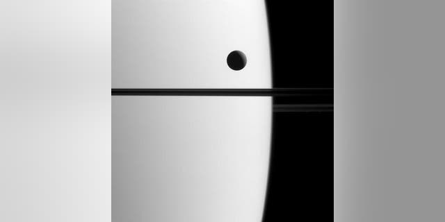 Saturn's moon Dione crosses the face of the ringed planet in an image obtained on May 21, 2015.