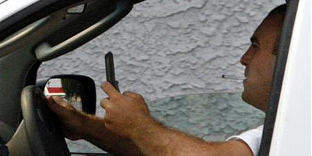 A man uses a cell phone while driving in Burbank, California June 25, 2008.