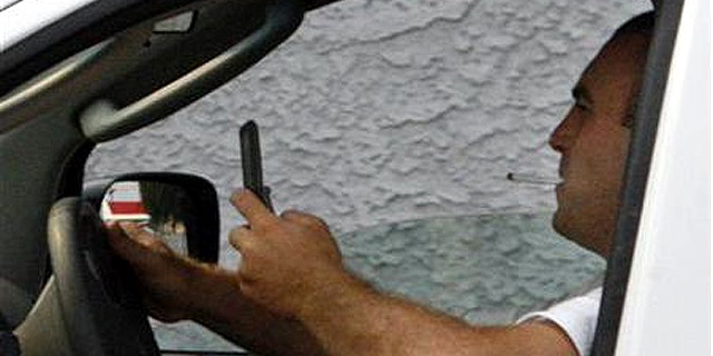 A man uses a cell phone while driving in Burbank, California June 25, 2008.