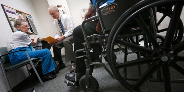 Nov. 26, 2013: A doctor speaks to patients at his office in Peoria, Ill.