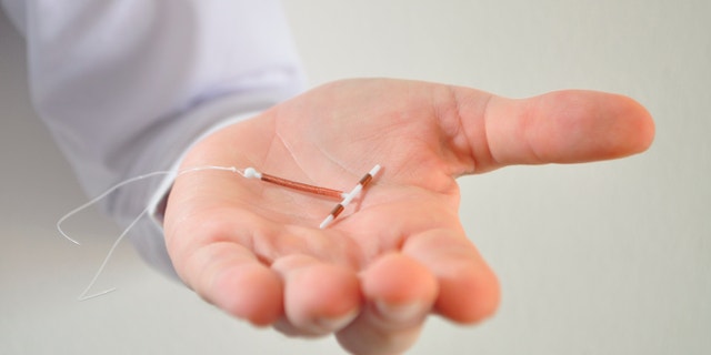 Holding an IUD birth control copper coil device in hand, used for contraception - front view