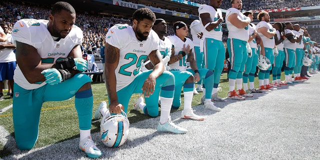 In this Sept. 11, 2017 file photo, from left, Miami Dolphins' Jelani Jenkins, Arian Foster, Michael Thomas, and Kenny Stills, kneel during the singing of the national anthem before an NFL football game against the Seattle Seahawks in Seattle.