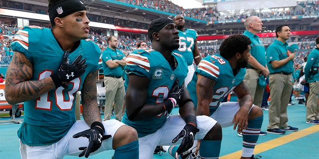 In this Sunday, Oct. 23, 2016, file photo, Miami Dolphins wide receiver Kenny Stills (10), free safety Michael Thomas (31) and defensive back Chris Culliver (29) kneel during the National Anthem before the first half of an NFL football game against the Buffalo Bills in Miami Gardens, Fla.