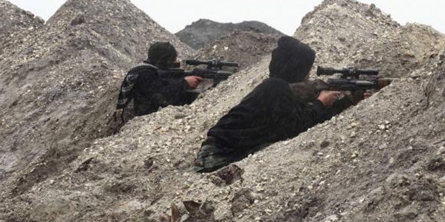 Jan. 5, 2015: Rebel fighters take positions behind sand barricades at al-Breij frontline, after what they said was an advance by them in al-Manasher and al-Majbal areas, where forces loyal to Syria's President Bashar al-Assad were stationed, in Aleppo. (REUTERS/ABDALGHNE KAROOF)
