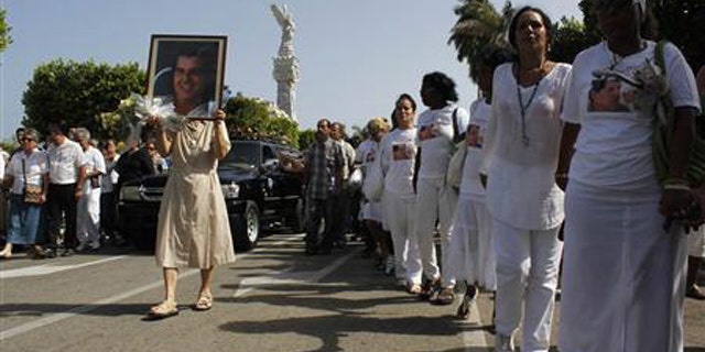 July 24, 2012: Members of the 'Ladies in White' opposition group march beside the funeral procession of Oswaldo Paya, one of Cuba's best-known dissidents, in Havana. (Reuters/File)