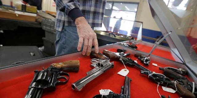 Feb. 6, 2015: Gun salesman arranges handguns in a display case in advance of a show at the Arkansas State Fairgrounds in Little Rock, Ark.