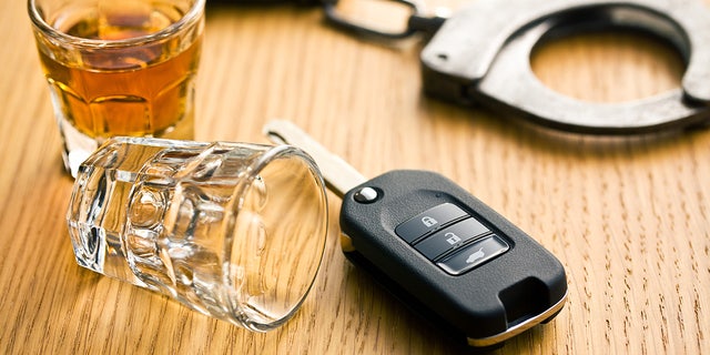 Car keys are seen laying next to two shot glasses and handcuffs.