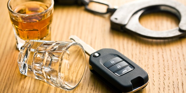 Car keys are seen laying next to two shot glasses and handcuffs.