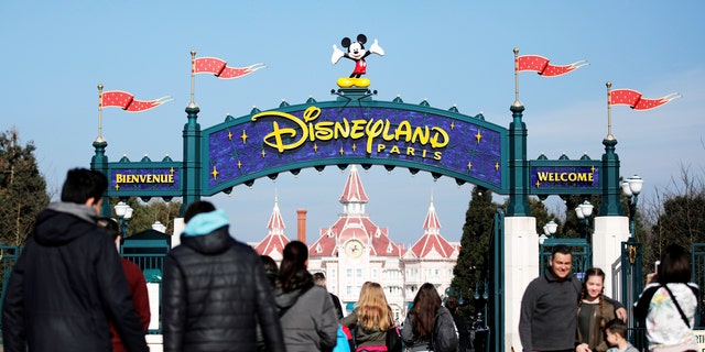 Les touristes posent juste devant l'entrée du parc à thème Disneyland Paris à Marne-la-Vallée, près de Paris, France.