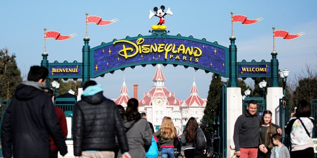 Tourists pose just outside the entrance at Disneyland Paris theme park in Marne-la-Vallee, near Paris, France.