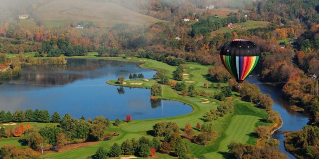 A colorful hot air balloon floating over a golf course
