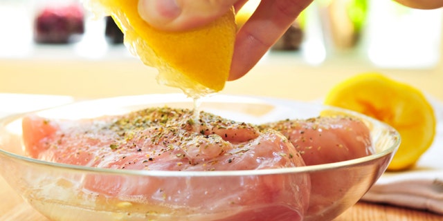 Marinating raw chicken breasts in lemon juice and herbs