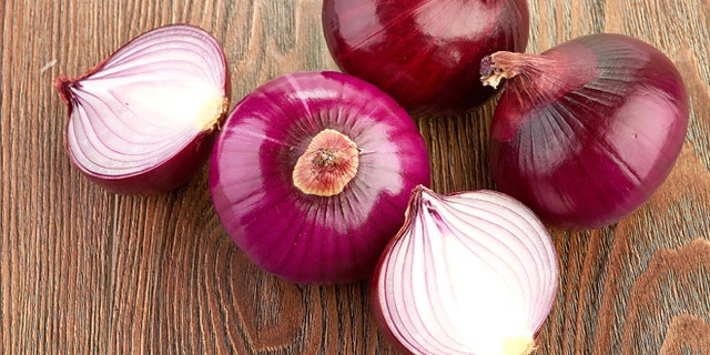 Fresh red onions on a wooden background