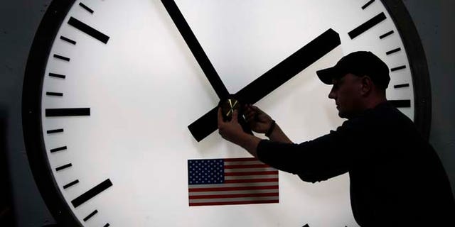 A worker adjusts the hands on a stainless steel tower clock in Medfield, Mass., in this March 7, 2014 file photo.