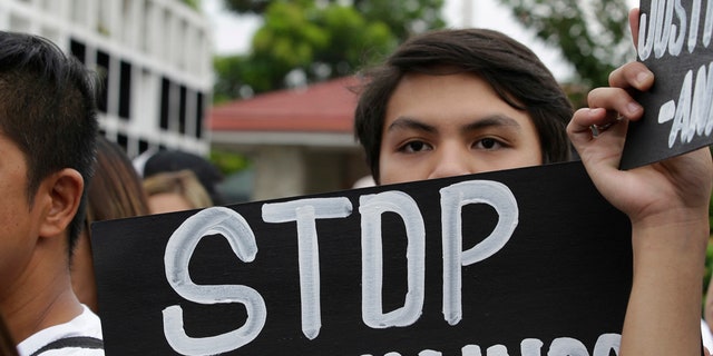 A supporter of Carl Angelo Arnaiz, a teen who was allegedly killed by police, carries a slogan during his burial ceremony in Manila, Philippines, Sept. 5, 2017.