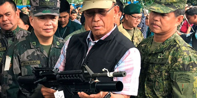 June 8: Philippines Defense Secretary Delfin Lorenzana (C) inspects a high-powered firearm seized from various hideouts of Islamist militants during their visit at a military camp in Marawi city