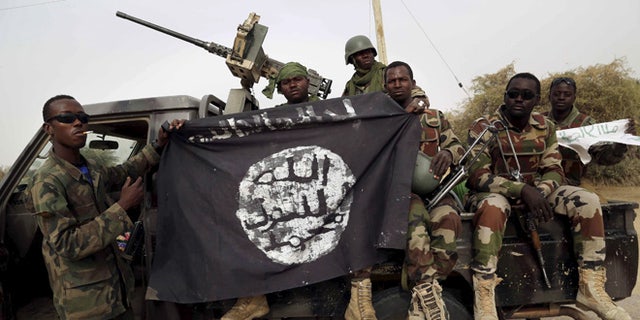 March 2015: Nigerian soldiers hold up a Boko Haram flag that they had seized in Damasak, Nigeria.
