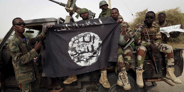 March 2015: Nigerian soldiers hold up a Boko Haram flag that they had seized in Damasak, Nigeria.