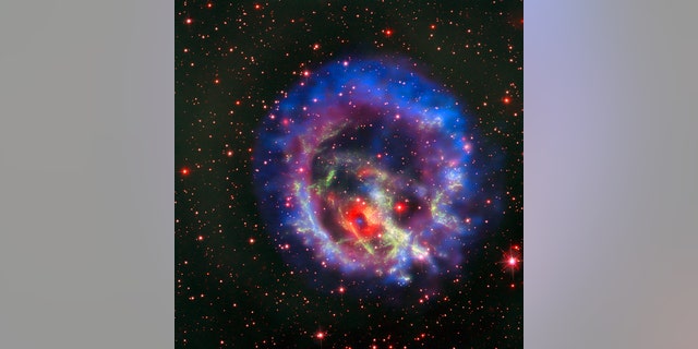 The new composite image of neutron star E0102, released on May 23, combines data from NASA's Chandra X-Ray Observatory (seen in blue and purple), the Multi Unit Spectroscopic Explorer instrument on the European Southern Observatory's Very Large Telescope in Chile (in bright red) and the Hubble Space Telescope (in dark red and green).
