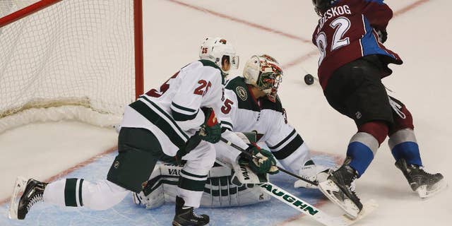 Colorado Avalanche left wing Gabriel Landeskog, right, of Sweden, flies past Minnesota Wild goalie Darcy Kuemper, center, as he stops shot while defenseman Jonas Brodin covers in the third period of the Wild's 3-0 victory in an NHL hockey game in Denver on Saturday, Oct. 11, 2014. (AP Photo/David Zalubowski)