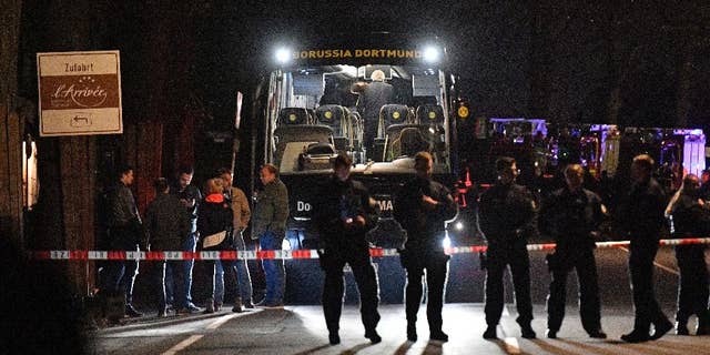 FILE - In this April 11, 2017 file photo police officers stand in front of Dortmund's damaged team bus after explosions which injured two people before the Champions League quarterfinal soccer match between Borussia Dortmund and AS Monaco in Dortmund, western Germany. (AP Photo/Martin Meissner, file)