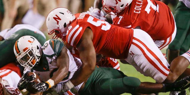 Miami running back Duke Johnson (8) is brought down by Nebraska defensive tackles Kevin Maurice (55) and Maliek Collins (7) in the second half of an NCAA college football game in Lincoln, Neb., Saturday, Sept. 20, 2014. Nebraska won 41-31. (AP Photo/Nati Harnik)