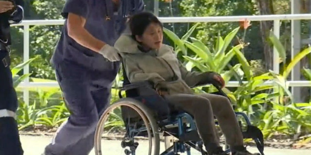 In this photo taken from the Australian Broadcasting Corporation video, South Korean backpacker Joohee Han, 25, is wheeled to a hospital after being rescued by helicopter, Thursday, June 7, 2018, in Tully, Queensland, Australia.