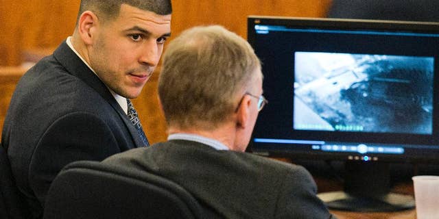 Feb. 20, 2015: Former NFL player Aaron Hernandez looks at his attorney as security footage is seen on a monitor during his murder trial at the Bristol County Superior Court in Fall River, Mass.
