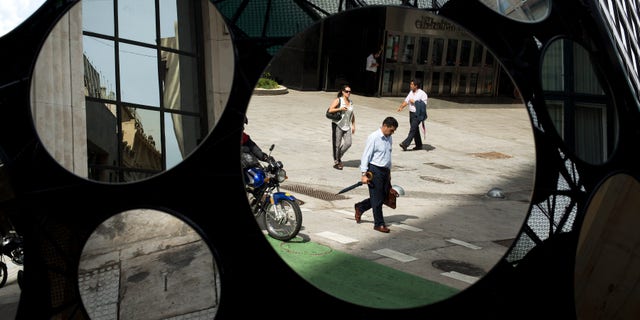 FILE - In this Tuesday, Jan. 28, 2014 file photo, office workers are reflected in a building's decorative mirrors in downtown Buenos Aires, Argentina. When Argentina fell into the economic abyss a decade ago after defaulting on its sovereign debt, Brazil suffered right along with it, nearly following its neighbor into insolvency. Now, with Argentina's economy again facing a currency plunge and inflation spike, its ability to inflict economic damage on Brazil has greatly diminished. (AP Photo/Victor R. Caivano, File)