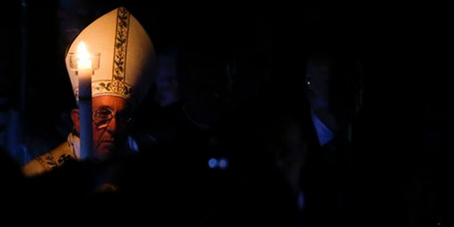 Pope Francis holds a white candle as he arrives for an Easter vigil service, in St. Peter's Basilica, at the Vatican, Saturday, March 26, 2016. (AP Photo/Gregorio Borgia)