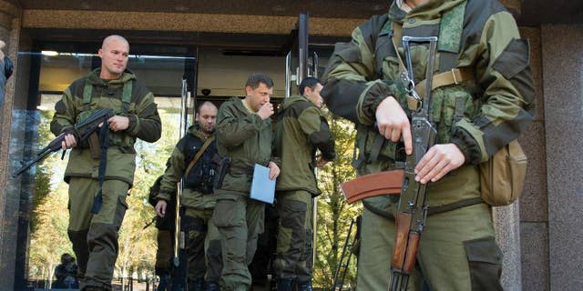 Alexander Zakharchenko, Prime Minister of the self proclaimed 'Donetsk People's Republic', centre, surrounded by pro-Russian rebels, walks in the town of Donetsk, eastern Ukraine Saturday, Oct. 11, 2014. A pro-Russian rebel leader says they have signed a demarcation deal with the Ukrainian government which sees the Ukrainians give up several villages including the one next to a strategic airport. (AP Photo/Dmitry Lovetsky)