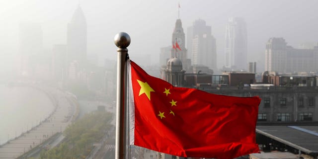 A Chinese national flag flutters against the office buildings at the Shanghai Bund shrouded by pollution and fog in Shanghai, China, Thursday, April 14, 2016. World finance officials who meet in Washington this week confront a bleak picture: Eight years after the financial crisis erupted, the global economy remains fragile and at risk of another recession. (AP Photo/Andy Wong)