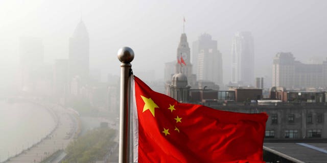 A Chinese national flag flutters against the office buildings at the Shanghai Bund shrouded by pollution and fog in Shanghai, China, Thursday, April 14, 2016. World finance officials who meet in Washington this week confront a bleak picture: Eight years after the financial crisis erupted, the global economy remains fragile and at risk of another recession. (AP Photo/Andy Wong)