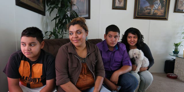 Adriana Gaytan, who came to Colorado in 1997 from the Mexican state of Zacatecas, second from left, sits at home with her children who were born in the U.S. from left to right, Osbaldo, 11, Oscar 13, Indhira, 14, and their dog Kissy, in Aurora, Colo., Thursday July 31, 2014. Gaytan will get a drivers license soon, as Colorado will begin issuing driver's licenses and identification cards to people who are in the country illegally or have temporary legal status. (AP Photo/Brennan Linsley)