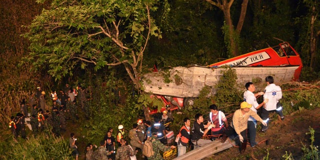 In this photo taken Wednesday, Oct. 23, 2013, Thai rescuers search for passengers of a bus that fell about 30 meters (98 feet) into the ravine on a curvy rural road in Lampang province, Thailand. The bus carrying worshippers home from a temple at the end of Buddhist Lent plunged into a ravine in northern Thailand, killing 22 passengers, police said Thursday. (AP Photo/Daily News) THAILAND OUT