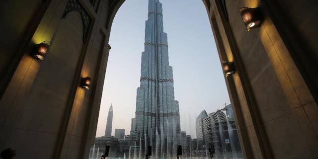 FILE - In this Monday, April 13, 2015, with the world tallest tower, Burj Khalifa, in the background, tourists and visitors watch and take photos of the Dubai Fountain in Dubai, United Arab Emirates. The Burj Khalifa announced Thursday, Nov. 5, it is selling tickets on the United Arab Emirates' weekend of Friday and Saturday for sunrise viewings. (AP Photo/Kamran Jebreili, File)