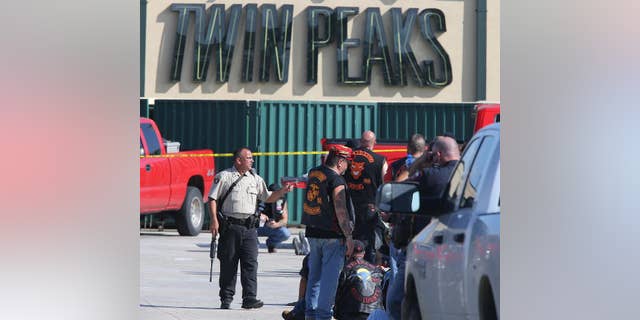 FILE - In this May 17, 2015, file photo, authorities investigate a shooting in the parking lot of the Twin Peaks restaurant in Waco, Texas. An attorney for one of the nearly 200 bikers arrested after a shooting melee outside the Waco, Texas, restaurant last year that left nine dead filed a motion Tuesday, May 17, 2016, seeking to disqualify the district attorney and others from participating in any of the pending cases. (AP Photo/Jerry Larson, File)